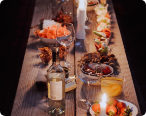  Picture of a wooden table with a dinner set up with candles appetizers and meals.